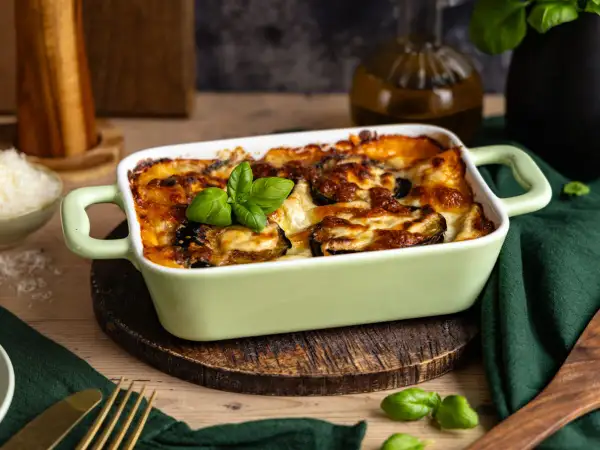 Herzhafte Auberginen Lasagne, goldbraun überbacken mit Käse und garniert mit frischem Basilikum. Ein Genuss für alle Sinne.