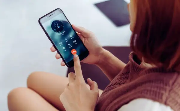 Kobieta trzyma telefon, na ekranie połączenie od nieznanego numeru. Zastanawiasz się, jak sprawdzić, czy telefon jest na podsłuchu?