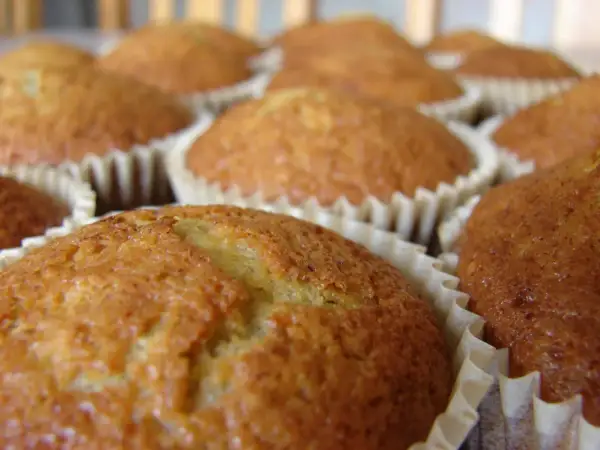 En närbild på flera gyllene bananmuffins utan socker i sina pappersformar. De ser saftiga och hembakade ut.