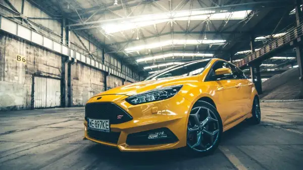 Żółty Ford Focus ST 2010 w hangarze, gotowy do akcji.