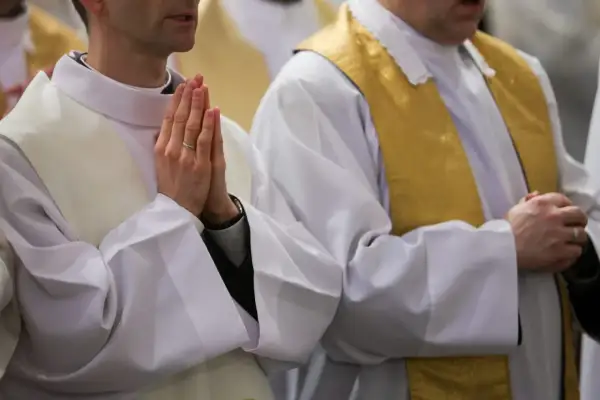 Dwóch księży w białych szatach z ozdobnymi stułami modli się. Ich dłonie złożone są do modlitwy. Ilu jest księży w Polsce?