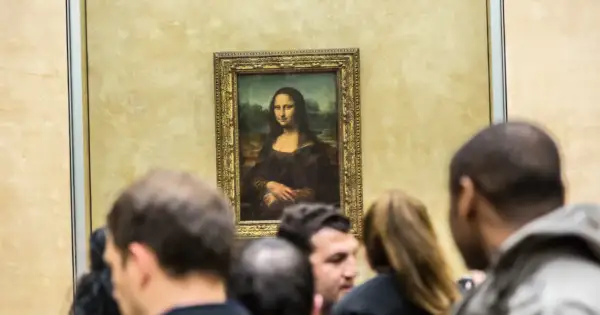 Mona Lisa z Isleworth, otoczona tłumem widzów, spogląda tajemniczo ze złotej ramy.