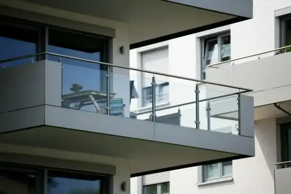 Nowoczesna loggia z przeszkloną balustradą, na której stoi stolik z krzesłami.