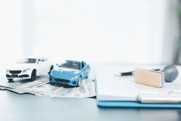 Modellini di auto su banconote, con documenti e timbro. Pensando a come disdire assicurazione auto prima della scadenza.