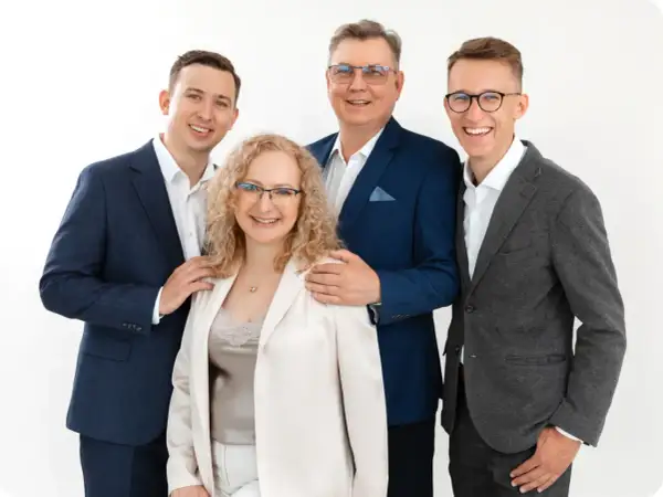 Cztery osoby w eleganckich strojach, uśmiechnięte, na białym tle.
