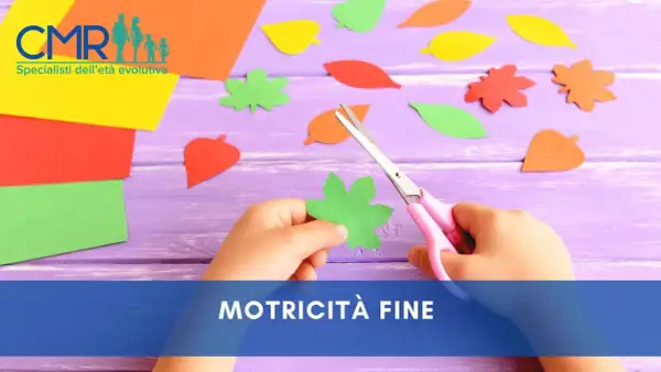 Mano di bambino che ritaglia forme di foglie colorate con forbici rosa, un'attività che stimola la motricità fine.