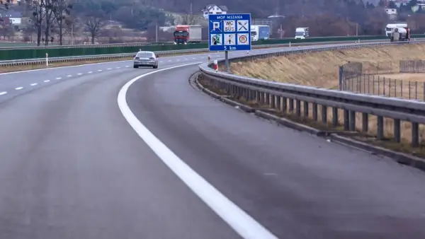 Autostrada z pasem awaryjnym. Znak informuje o MOP MSZANA, toalecie, busach i odległości 5 km.