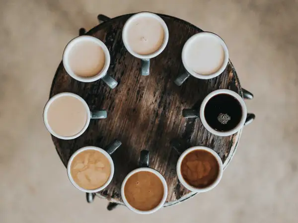 Åtta koppar kaffe i olika nyanser, från mörk espresso till ljus latte. En visuell guide till skillnad mellan latte och cappuccino.