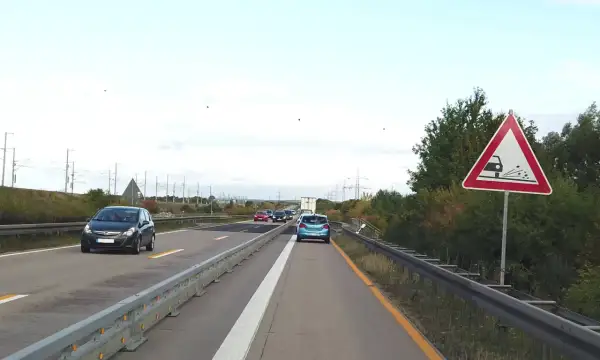 Achtung, stau schild warnt vor schleudernder Fahrbahn. Autos fahren auf der Autobahn.