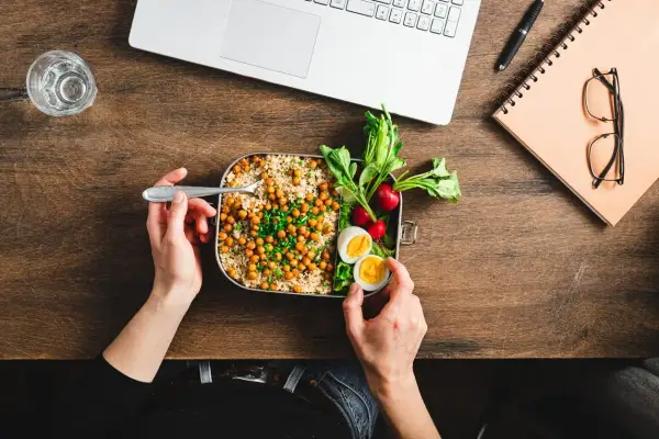 Pausa pranzo salutare con couscous, ceci, uova e verdure. La normativa sulla pausa pranzo incoraggia pasti equilibrati per il benessere lavorativo.