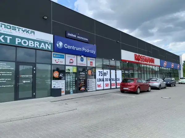 Budynek z szyldami "Diagnostyka", "Centrum Podróży", "Unilink Ubezpieczenia" i "Rossmann".