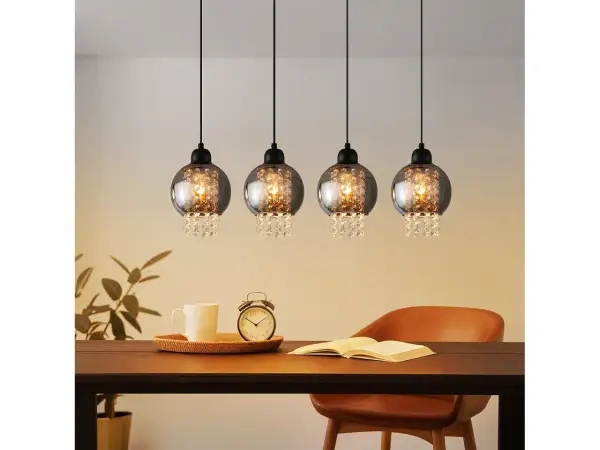 Elegancka lampa wisząca kryształowa z czterema kulistymi kloszami, ozdobiona błyszczącymi kryształkami, tworzy magiczny blask nad stołem.