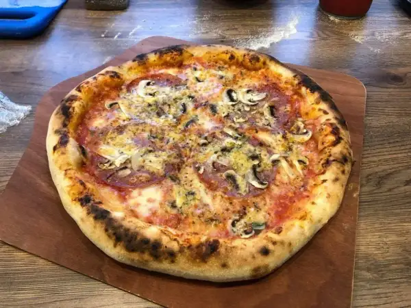 Pyszna pizza z pieczarkami i salami, idealnie wypieczona. Dowodzi, ile nagrzewa się kamień do pizzy, by uzyskać taki efekt.