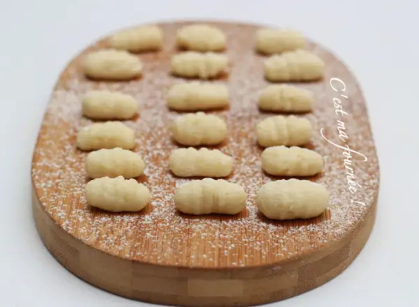 Gnocchis faits maison, une délicieuse pâte italienne à base de pomme de terre, saupoudrés de sucre glace sur une planche en bois.