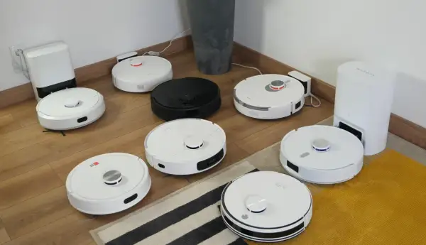 Ranking robotów sprzątających: białe i czarne modele na drewnianej podłodze, gotowe do testów.