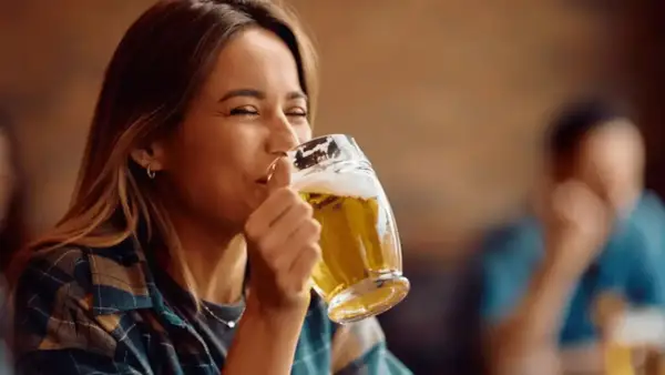 Donna sorridente beve una weizen beer in un pub.