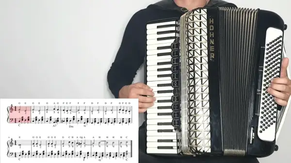 Akordeonista gra "Sto lat", nuty literowe pokazują melodię.