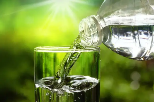 Verre rempli d'eau pure, versée d'une bouteille. L'eau du robinet, sans TDS, est rafraîchissante.