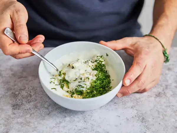 Ein cremiger Knoblauchdip mit frischer Petersilie wird zubereitet, perfekt als Beilage zu Flammlachs.
