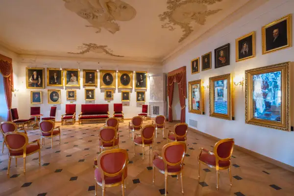 Elegancka sala z portretami i fotelami, idealna do zwiedzania najciekawszych muzeów w Krakowie.