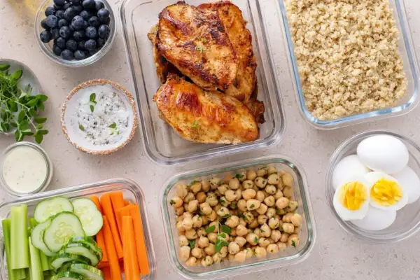 Vorbereitete Mahlzeiten für clean eating: Hähnchenbrust, Quinoa, Kichererbsen, Gemüse-Sticks, Blaubeeren und hartgekochte Eier.