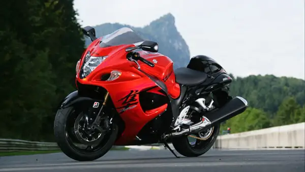 Czerwono-czarny motocykl Suzuki Hayabusa 1300 na drodze, z górami w tle.