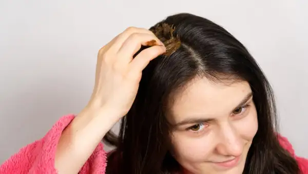 Kobieta nakłada na skórę głowy naturalną maskę, szukając sposobu, co zrobić, żeby włosy szybciej rosły.