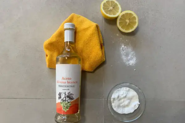 Aceto di vino bianco, bicarbonato, limoni e un panno giallo per lavare i pavimenti con aceto e ammorbidente.