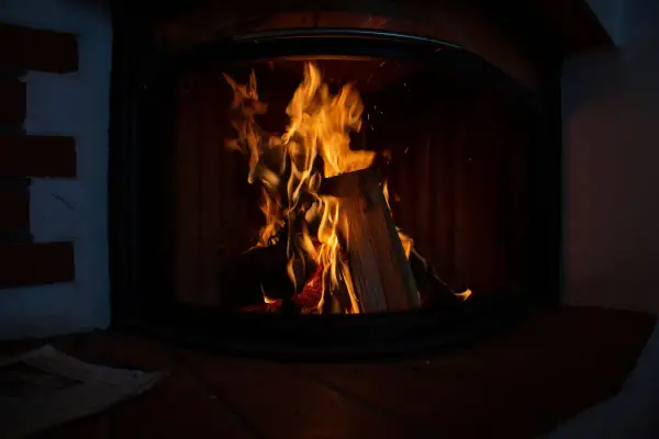 Flammen lodern im Kaminofen. Ein Zeitungsstapel liegt davor. Der Ofen ist nicht stillgelegt, es gibt Ausnahmen für gemütliche Abende.