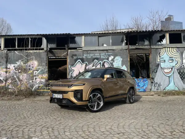 Złoty SsangYong Actyon na tle zniszczonego budynku z graffiti.