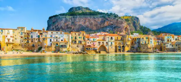 Case colorate affacciate sul mare di Cefalù, con la Rocca a dominare lo sfondo.