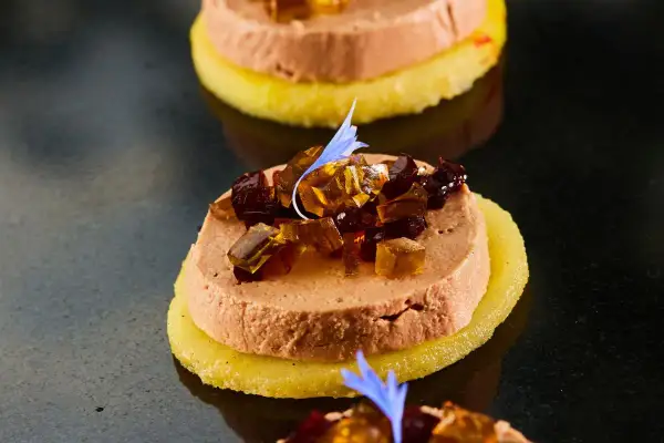 Délicieuse terrine de foie gras sur une tranche d'ananas, garnie de dés de gelée et d'une fleur bleue. Un vrai régal pour savoir comment démouler une terrine de foie gras.