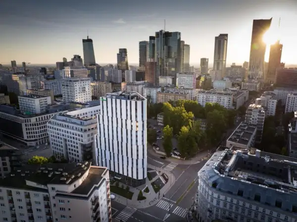 Widok na miasto z nowoczesnym budynkiem Holiday Inn Twarda w centrum. W tle wieżowce i zieleń.