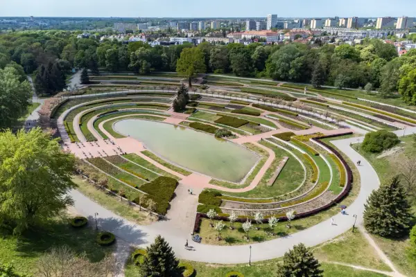 Widok z lotu ptaka na park Cytadela z jeziorem, tarasami i alejkami. W tle zabudowania miejskie.