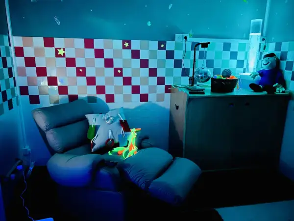 Chaise confortable et lumineuse pour une séance snoezelen, avec des étoiles au mur et une colonne à bulles.