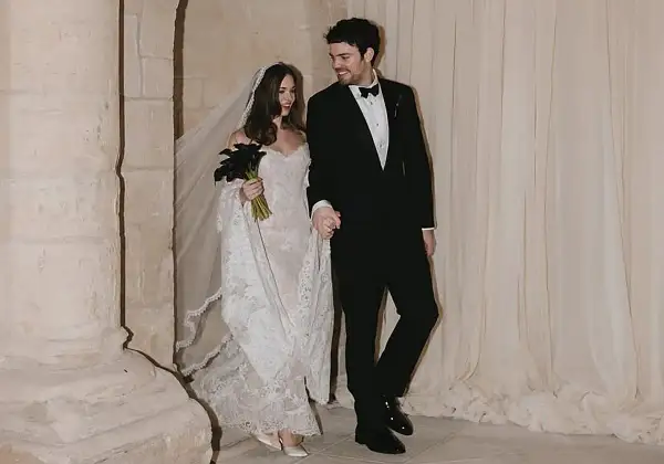 Novia con velo y ramo de **stella banderas** negras, y novio de traje, saliendo de una iglesia.