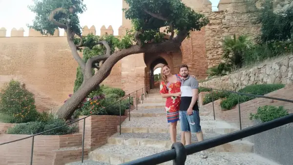 Pareja posando en escalinatas de piedra con un árbol retorcido y murallas de cañarete Almería de fondo.