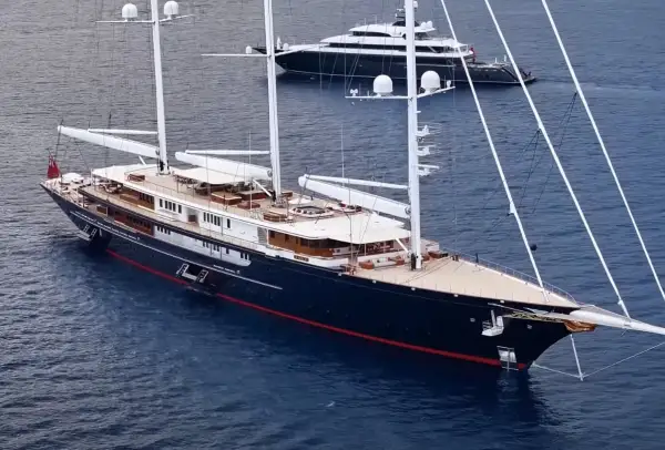 Il maestoso yacht Koru, con i suoi lussuosi interni, naviga in acque blu. Un altro yacht più piccolo è visibile sullo sfondo.