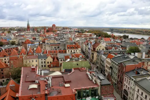 Widok na **Toruń stare miasto** z lotu ptaka. Czerwone dachy kamienic, kościelne wieże i Wisła w tle.