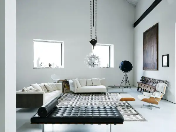 Soggiorno moderno con divani bianchi, chaise longue in pelle nera e un'iconica poltrona. Un ambiente che evoca case eleganti e raffinate.