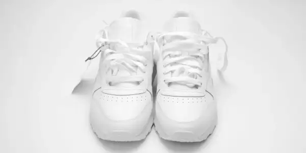 Un paio di scarpe da ginnastica bianche, nuove di zecca, con etichetta. Chissà a quanti gradi si lavano le scarpe per mantenerle così immacolate.