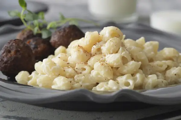 En portion stuvade makaroner snabbt vis med köttbullar och en kvist örter.