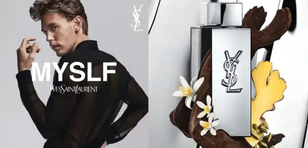 Młody mężczyzna w czarnej, prześwitującej koszuli, obok flakonu perfum Yves Saint Laurent MYSLF, otoczony drewnem i kwiatami.