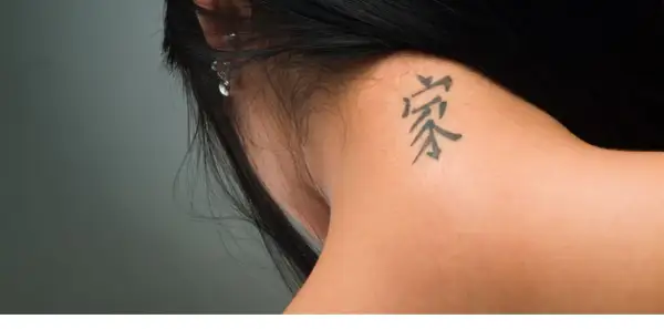 Mały tatuaż na karku, symbolizujący dom i rodzinę, dyskretnie ozdabia skórę.