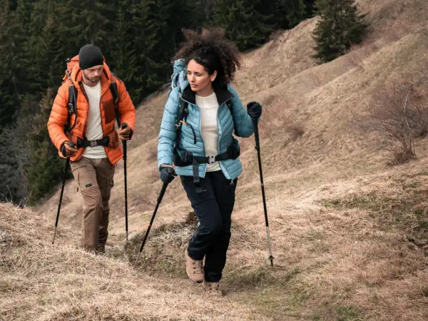 Para trekking w górach, ważne są odpowiednie **końcówki do kijków w góry**. Para turystów w odzieży outdoorowej pokonuje górski szlak.