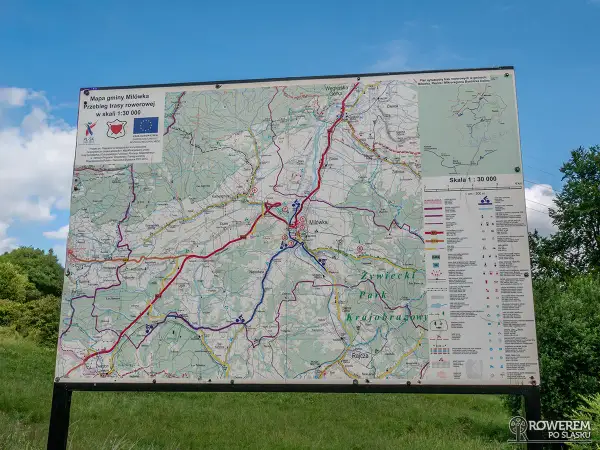 Mapa gminy Milówka pokazuje przebieg niebieskiego szlaku rowerowego. Widać liczne drogi i ścieżki, a także legendę z symbolami.
