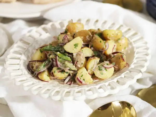 En krämig potatissallad med rödlök och örter, ser ut att vara den godaste potatissalladen för en sommarbuffé.