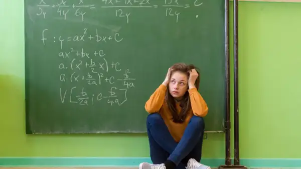 Dziewczyna zmagająca się z zadaniami matematycznymi na tablicy, symbolizująca dyskalkulię u dorosłych.