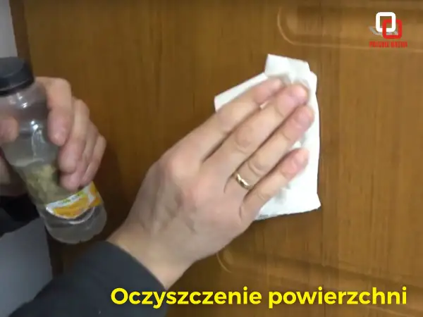 Rysy na drzwiach z okleiny znikają dzięki czyszczeniu. Dłoń z pierścionkiem przeciera powierzchnię.