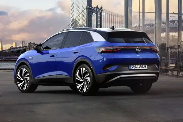 Niebieski Volkswagen ID.4 z imponującym zasięgiem, zaparkowany na tle miejskiej panoramy z mostem.